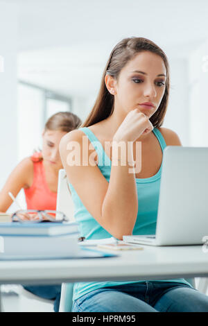 Young teen students in the classroom using laptops and sitting at school desk Stock Photo