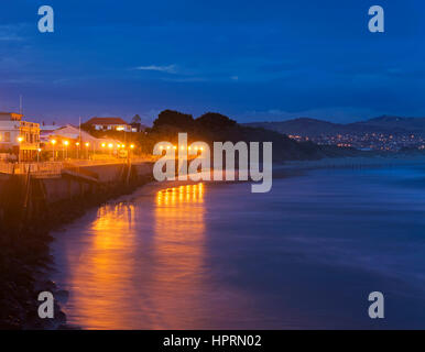 Dunedin, Otago, New Zealand. View along the illuminated esplanade at dusk, St Clair, lights reflected in the Pacific Ocean. Stock Photo