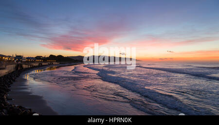 Dunedin, Otago, New Zealand. View over the Pacific Ocean off St Clair Beach at dawn, pink sky reflected in water. Stock Photo