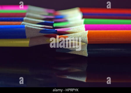 Close up of colored pencils on black reflective surface. Stock Photo