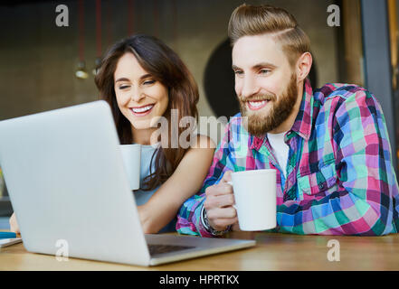 Happy couple looking while drinking coffee in cafe Stock Photo