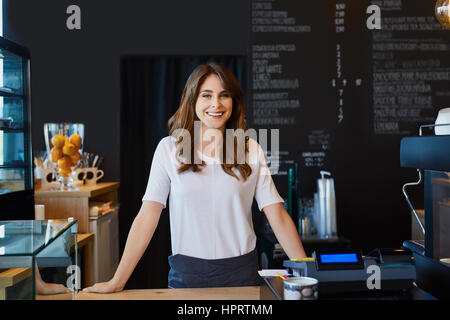 Beautiful female barista standing behind the bar in cafe Stock Photo