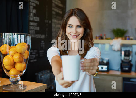 Young woman serving coffee in cafe Stock Photo