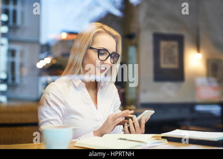 Young business woman using her smartphone in cafe during coffee break Stock Photo