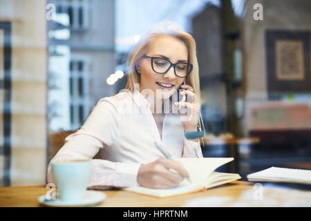 Busy businesswoman working in a cafe talking on the phone Stock Photo