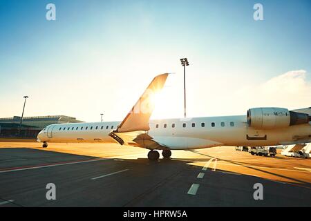 Daily life at the international airport. The airplane is taxiing to the runway during sunset. Stock Photo