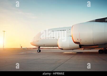 Traffic of the airport at the sunset. Huge airplane is taxiing to the runway - selective focus Stock Photo