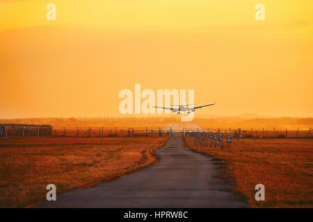 Airplane landing at the airport during golden sunset. Stock Photo