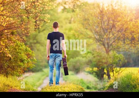 Guy with guitar. Handsome young man is enjoying in springtime. Stock Photo