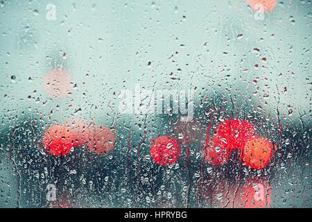 Heavy rain. Raindrop on the window of the car. Abstract blur bokeh of traffic and car light. Stock Photo