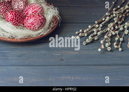 Still life with Pysanka, decorated Easter eggs, dry willow branches on black wooden background, copy space Stock Photo