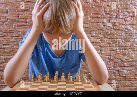 Serious clever boy looking at chess board. Game, education concept Stock Photo