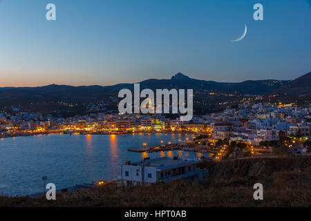 Tinos city and harbor in the afternoon with the moon rising above the sky Stock Photo