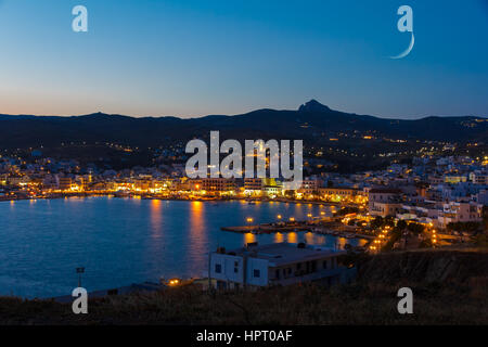 Tinos city and harbor in the afternoon with the moon rising above the sky Stock Photo