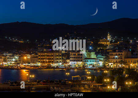 Tinos city and harbor in the afternoon with the moon rising above the sky Stock Photo