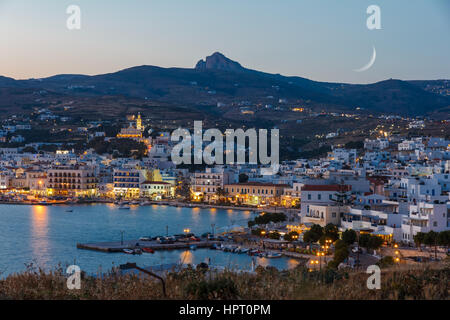 Tinos city and harbor in the afternoon with the moon rising above the sky Stock Photo