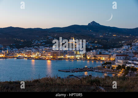 Tinos city and harbor in the afternoon with the moon rising above the sky Stock Photo