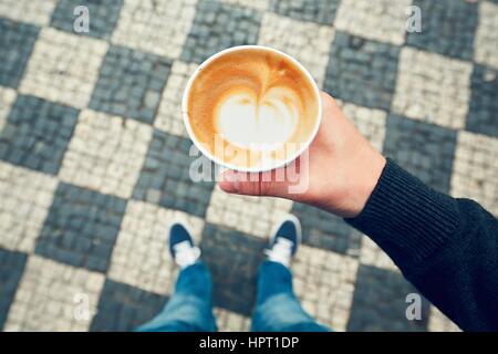 Morning coffee take away. Man is holding paper cup with coffee on the street. Stock Photo