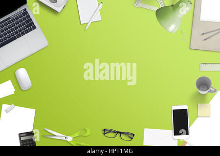 Mess on office desk with free space for text. Laptop computer, smart phone and office work accessories. Top view of green work space. Stock Photo