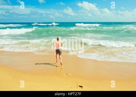 Young man is running to the sea Stock Photo