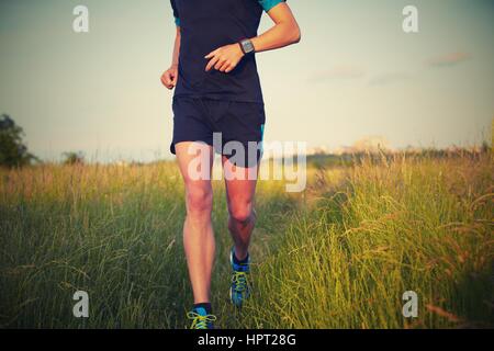 Young man is running on summer meadow - lovely sunset light Stock Photo