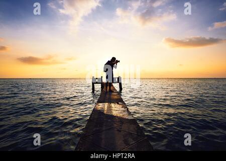 Young photographer is taking photos at the sunset. Stock Photo