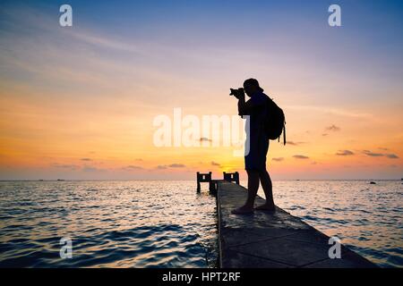 Young photographer is taking photos at the sunset. Stock Photo
