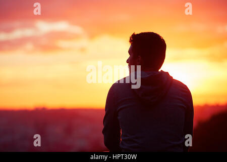 Young man is looking at the sunrise. Stock Photo