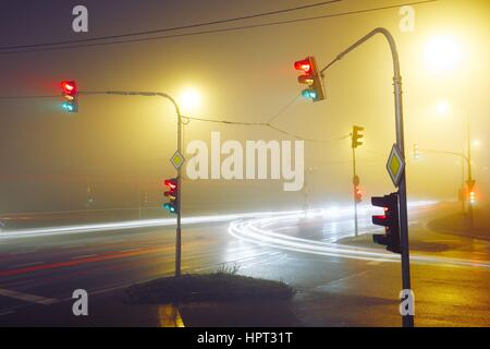 Traffic lights - crossroad in the foggy night Stock Photo
