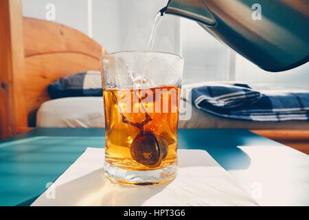 Hot tea in glass cup on the bedside table in bedroom. Stock Photo