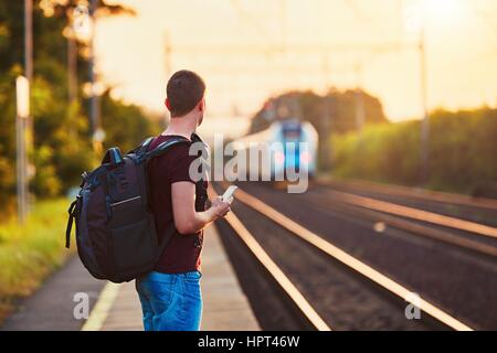 Traveler is late at the train station. Young man with backpack missed the train and waiting for next. Stock Photo