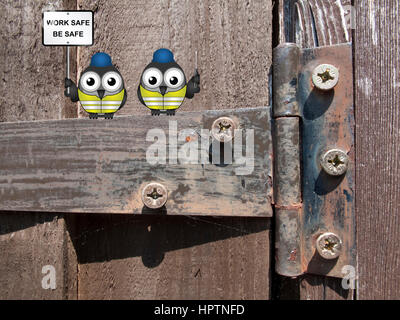 Comical bird construction workers perched on an old rusty hinge with health and safety message work safe be safe sign Stock Photo