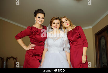 Cute blonde bride with bridesmaids posed on room at wedding morning day. Stock Photo