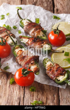 jalapeno peppers with feta cheese wrapped in bacon close-up on the table. Vertical Stock Photo