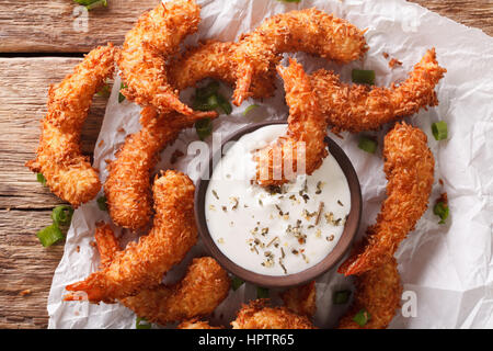 prawns fried in coconut close-up and cream sauce on the parchment on the table. Horizontal view from above Stock Photo