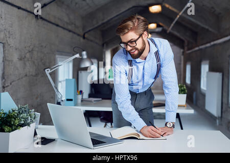 Happy hipster working with laptop from coworking office Stock Photo