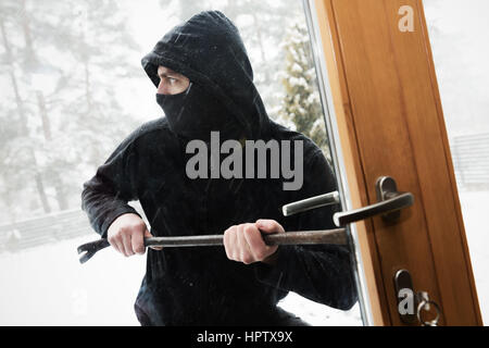 house robbery - robber trying open door with crowbar Stock Photo