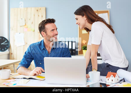 Two happy architects, designers talking at office sitting at table in office Stock Photo