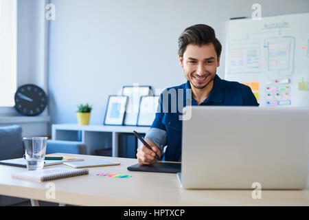Graphic designer sketching new project on tablet working with laptop in office Stock Photo