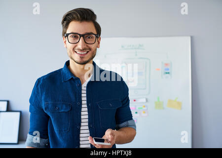 Portrait of happy web designer, standing in office developing new responsive website. Stock Photo