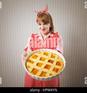 Retro housewife holding hot italian pie. Stock Photo