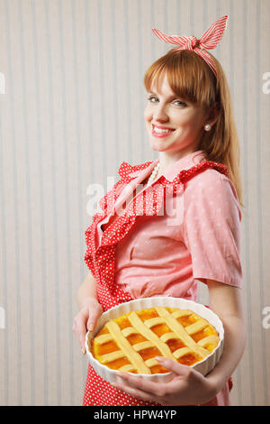 Retro housewife holding hot italian pie. Stock Photo