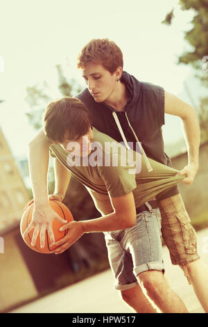 Boys playing a game of basketball on an outdoor court. Stock Photo