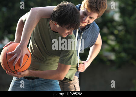 Boys playing a game of basketball on an outdoor court. Stock Photo