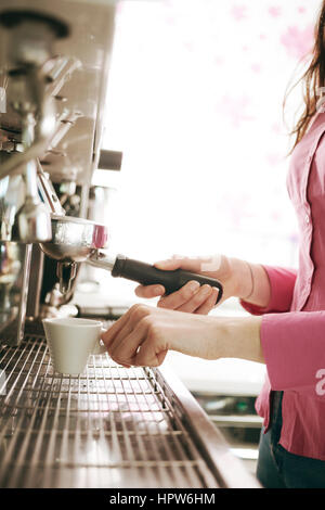 Female barista making coffee with an espresso coffee machine Stock Photo