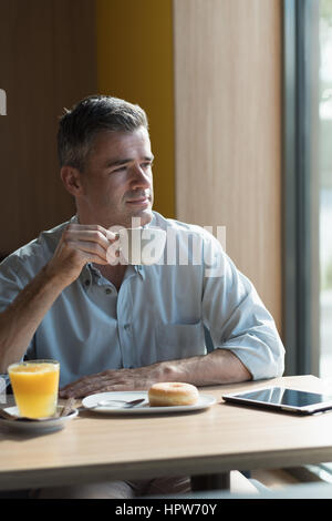 Businessman at the bar having a cup of coffee and looking through a window, healthy lifestyle concept Stock Photo