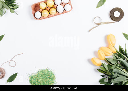 Easter composition on the white background: tulips, painted eggs, ribbon. Top view. Stock Photo