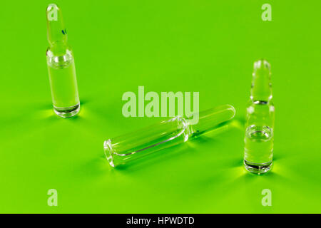 Three glass ampules of medicine on green background Stock Photo