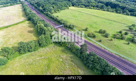 Aerial view of train rail tracks through English, green countryside, on a summer day . Stock Photo