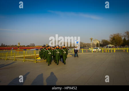 BEIJING, CHINA - 29 JANUARY, 2017: Chinese army soldiers marching on Tianmen square wearing green uniform coats and black hats, beautiful blue sky. Stock Photo